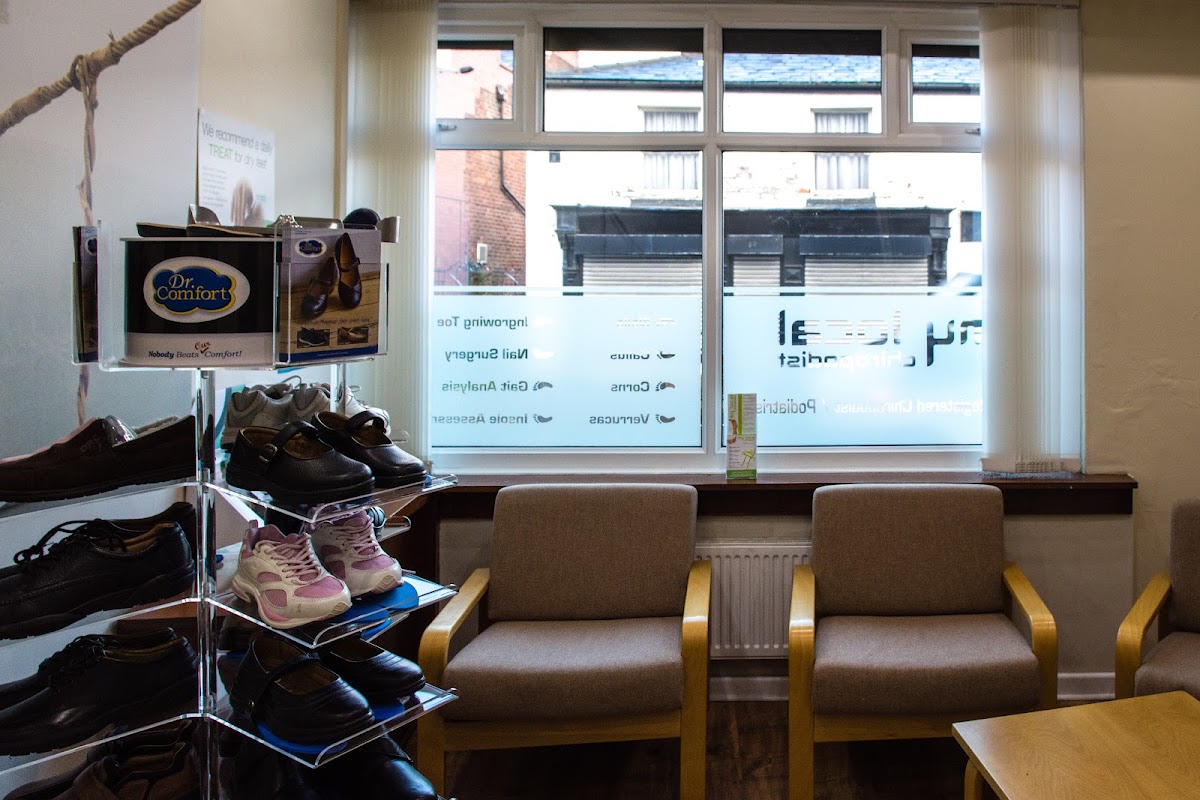 The waiting room at My Local Chiropodist, with seating and a footwear display